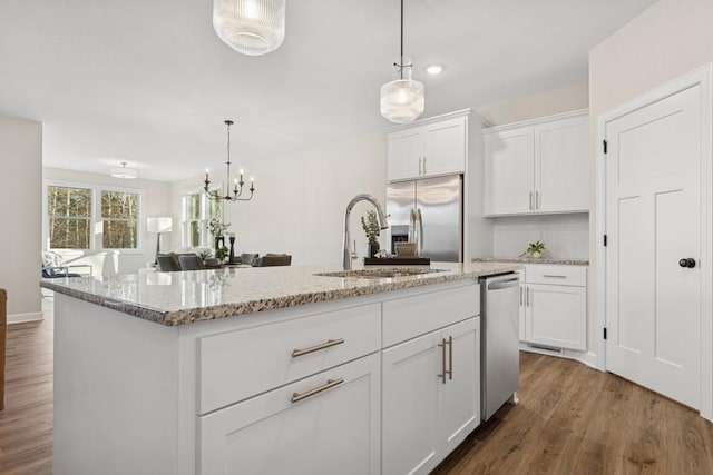 kitchen with stainless steel appliances, a sink, dark wood-style floors, white cabinetry, and hanging light fixtures