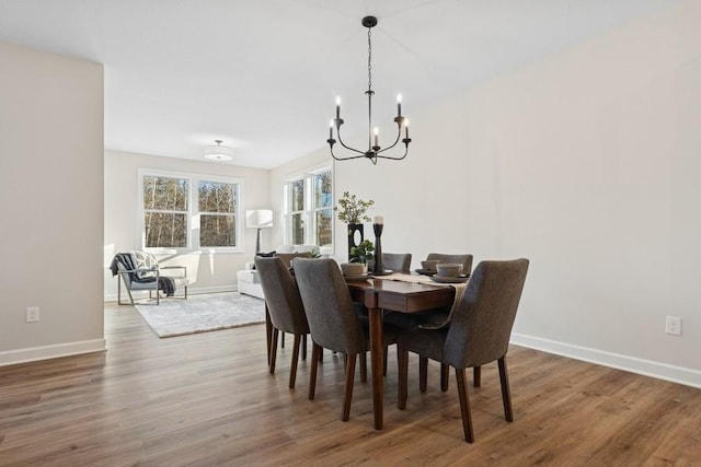 dining space featuring a chandelier, wood finished floors, and baseboards