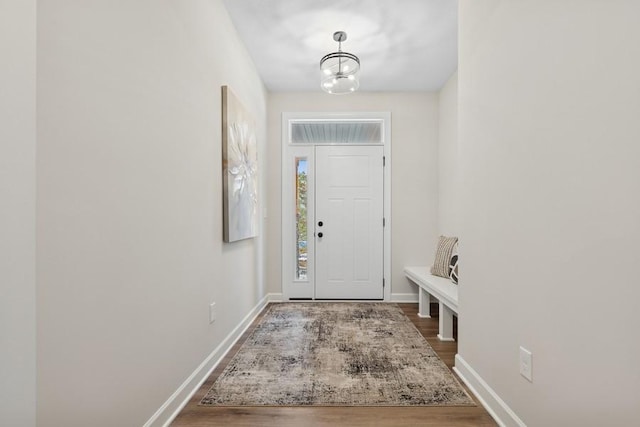entrance foyer featuring baseboards, wood finished floors, and a chandelier