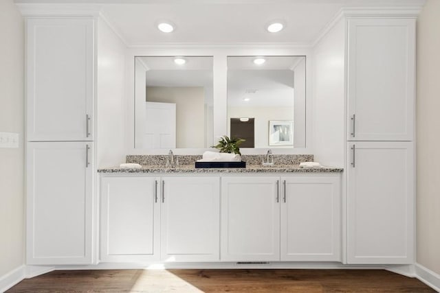 bathroom with double vanity, wood finished floors, baseboards, and recessed lighting