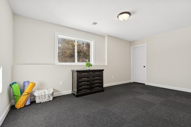 unfurnished bedroom featuring dark carpet and baseboards