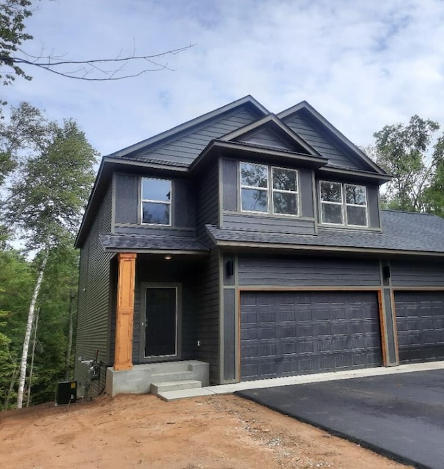 view of front facade featuring an attached garage, driveway, and central AC