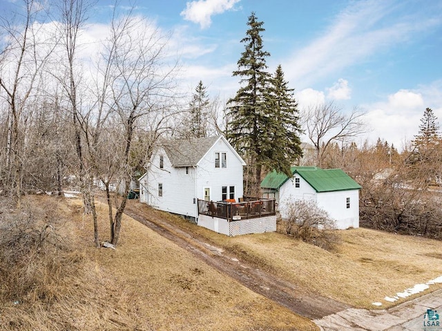 view of side of property with a wooden deck, an outbuilding, and a lawn
