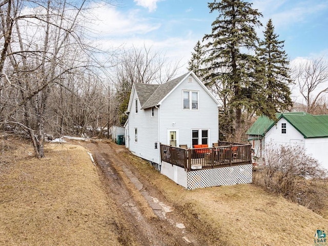 rear view of property featuring a wooden deck and a shingled roof
