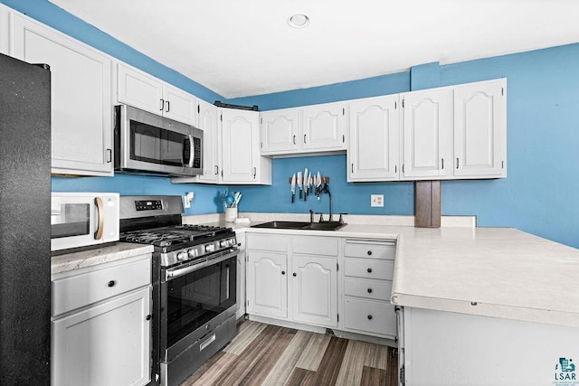 kitchen featuring appliances with stainless steel finishes, a sink, light countertops, and white cabinetry
