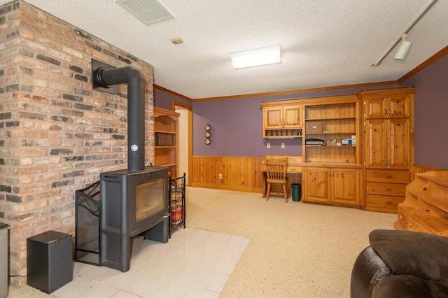 1749 Avocet Ln, Mound, MN 55364 - living area with wainscoting, a wood stove, a textured ceiling, wooden walls, and crown molding