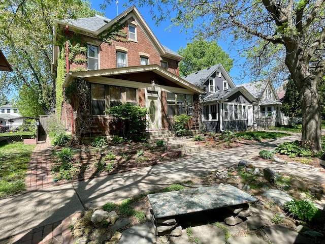view of front of house with brick siding and a sunroom