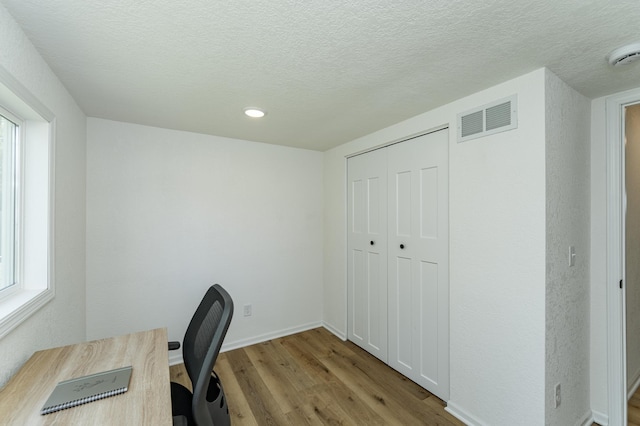unfurnished office featuring wood finished floors, healthy amount of natural light, a textured ceiling, baseboards, and recessed lighting