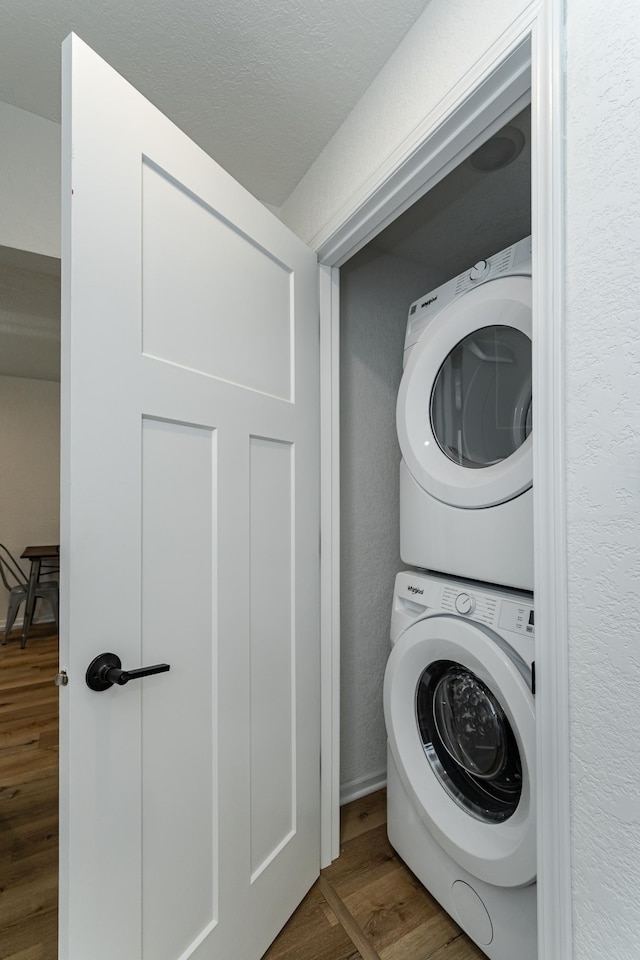 laundry room with stacked washing machine and dryer and wood finished floors