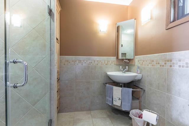 22005 Statesboro Trl, Clitherall, MN 56524 - bathroom featuring tile walls, a stall shower, wainscoting, a sink, and tile patterned flooring