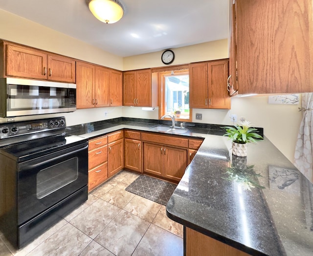 kitchen featuring stainless steel microwave, black / electric stove, a sink, and brown cabinets