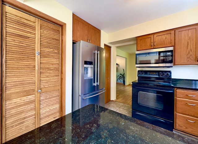 kitchen featuring appliances with stainless steel finishes, brown cabinets, and dark stone counters