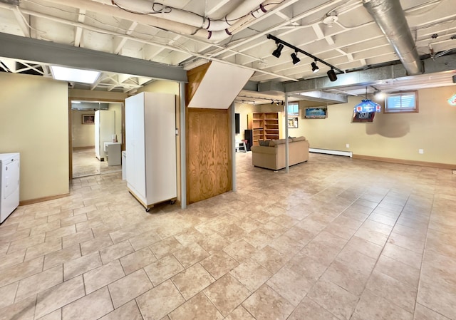 below grade area featuring washing machine and dryer, baseboards, a baseboard radiator, and track lighting