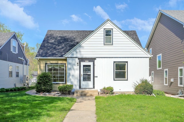 view of front of property featuring a front yard, a shingled roof, and ac unit