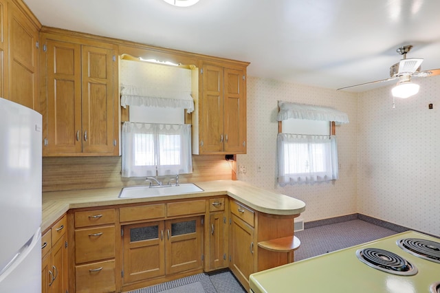 kitchen featuring freestanding refrigerator, plenty of natural light, a sink, light countertops, and wallpapered walls