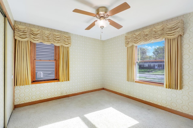 carpeted spare room featuring baseboards and a ceiling fan