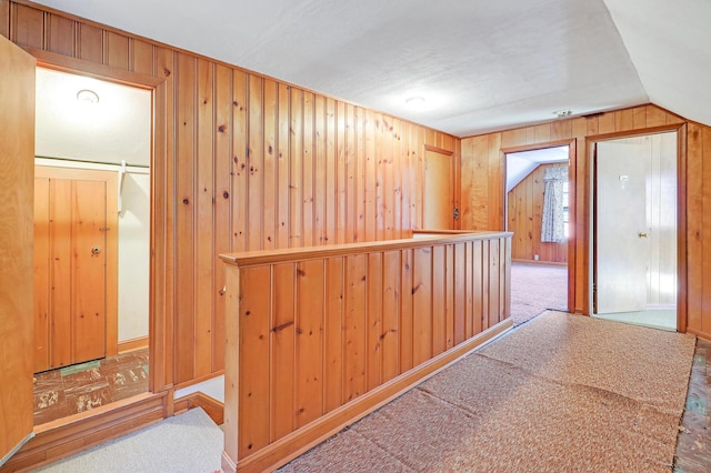 corridor featuring wooden walls and carpet floors