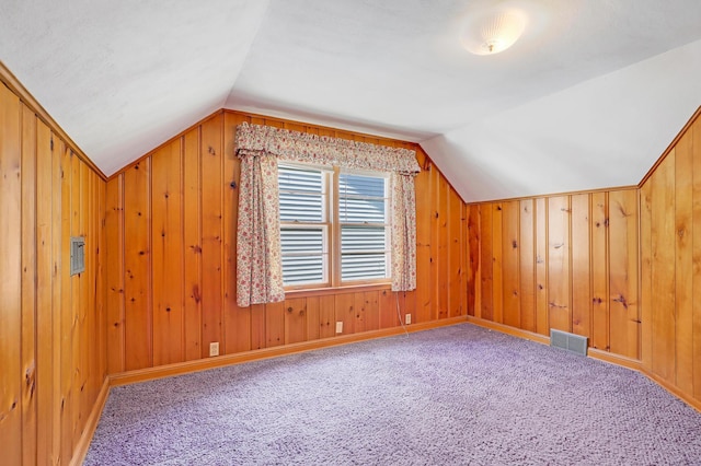 bonus room featuring vaulted ceiling, carpet floors, wooden walls, and baseboards