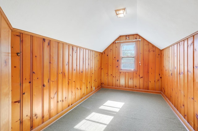additional living space with lofted ceiling, carpet flooring, and wood walls