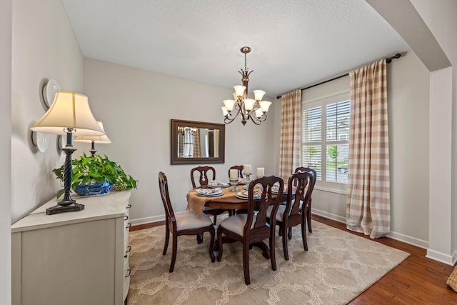3121 Wild Flower Trl, Medina, MN 55340 - dining space with a chandelier, baseboards, wood finished floors, arched walkways, and a textured ceiling