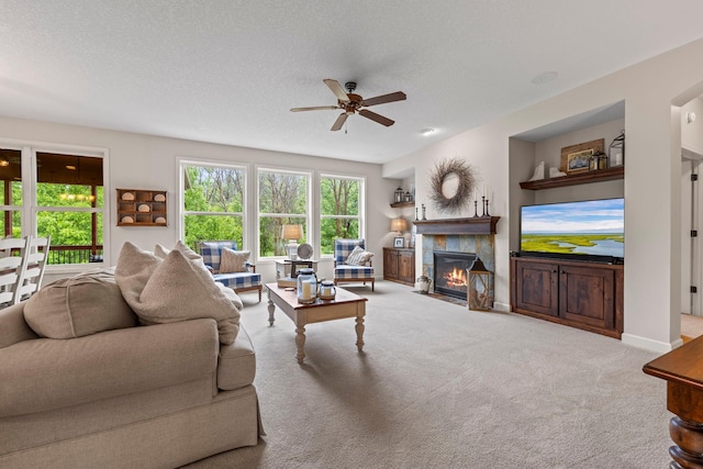 3121 Wild Flower Trl, Medina, MN 55340 - carpeted living room featuring a ceiling fan, a tiled fireplace, a textured ceiling, and baseboards