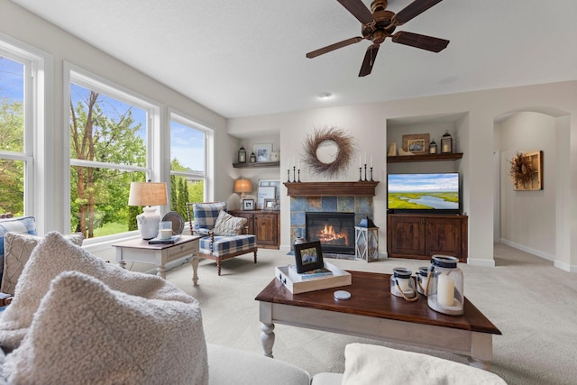 3121 Wild Flower Trl, Medina, MN 55340 - living room featuring carpet, a fireplace, a ceiling fan, baseboards, and arched walkways