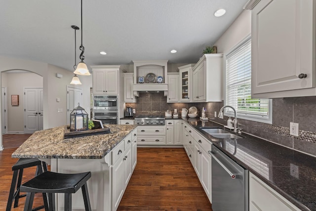 3121 Wild Flower Trl, Medina, MN 55340 - kitchen featuring stainless steel appliances, a sink, a kitchen breakfast bar, dark wood-style floors, and arched walkways