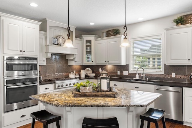 3121 Wild Flower Trl, Medina, MN 55340 - kitchen featuring appliances with stainless steel finishes, a sink, a kitchen bar, white cabinetry, and a center island
