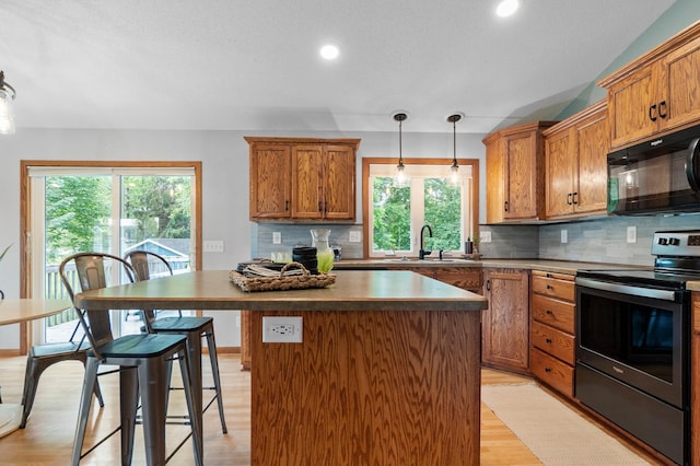 2820 Wilderness Ridge Rd SE, Alexandria, MN 56308 - kitchen with black microwave, electric range, a center island, backsplash, and brown cabinetry