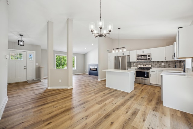 kitchen with appliances with stainless steel finishes, a sink, vaulted ceiling, open floor plan, and a center island