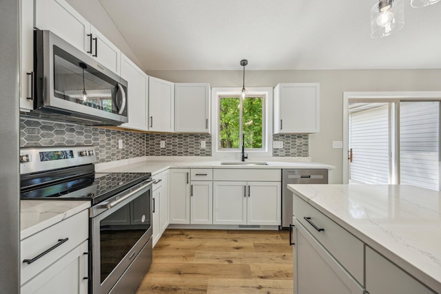 kitchen featuring stainless steel appliances, a sink, tasteful backsplash, light wood-style flooring, and white cabinets