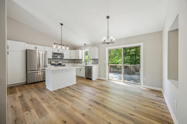 kitchen with stainless steel appliances, a chandelier, lofted ceiling, light countertops, and tasteful backsplash