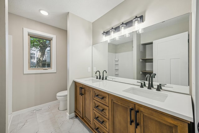 full bath featuring baseboards, marble look tiles, toilet, and double vanity