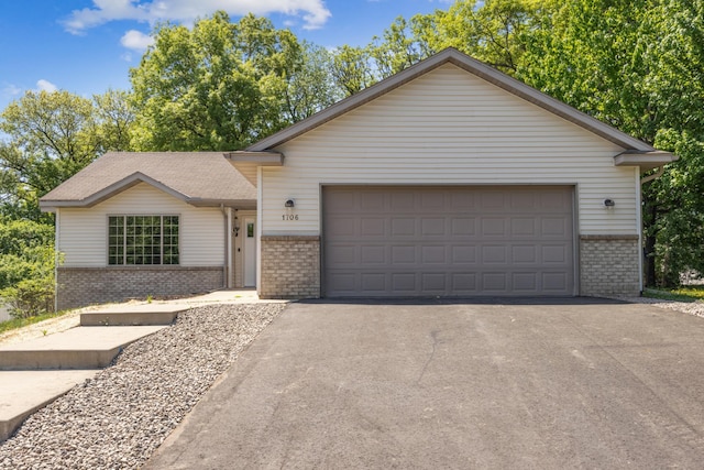 ranch-style house with brick siding, asphalt driveway, and an attached garage