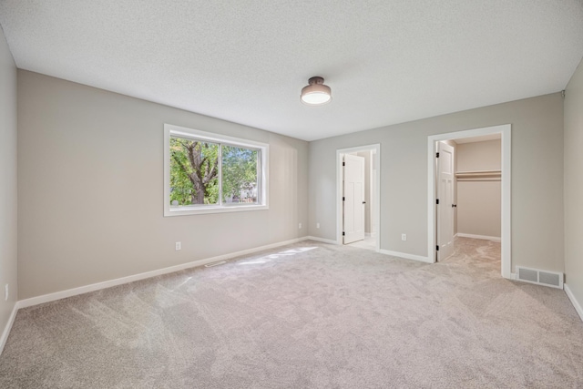 1706 36th St S, Saint Cloud, MN 56301 - unfurnished bedroom with a walk in closet, carpet floors, baseboards, a textured ceiling, and a closet