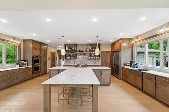 18565 Revere Ave, Spring Lake Twp, MN 55372 - kitchen with open shelves, light wood-type flooring, a large island, a sink, and plenty of natural light