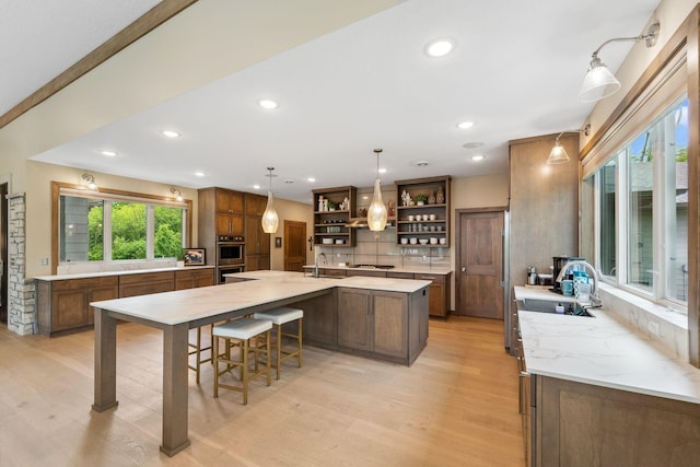 18565 Revere Ave, Spring Lake Twp, MN 55372 - kitchen featuring open shelves, a sink, light wood-type flooring, a large island, and stainless steel double oven