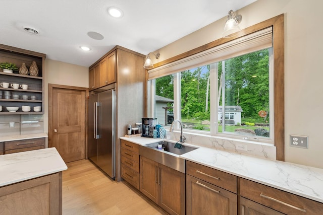 18565 Revere Ave, Spring Lake Twp, MN 55372 - kitchen with high end fridge, a sink, open shelves, light wood-style flooring, and light stone countertops