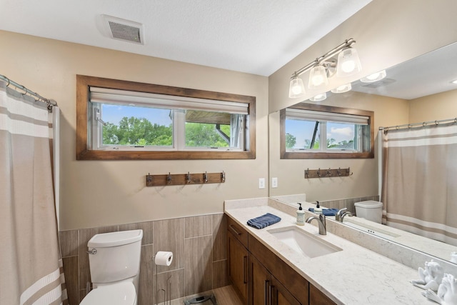 18565 Revere Ave, Spring Lake Twp, MN 55372 - bathroom featuring toilet, vanity, a wainscoted wall, tile walls, and a shower with curtain