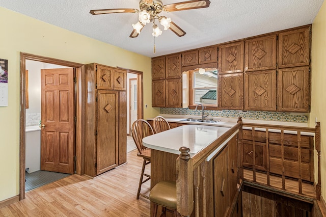 2628 River Rd, Sterling Twp, WI 54024 - kitchen with a sink, light wood finished floors, ceiling fan, brown cabinets, and a textured ceiling