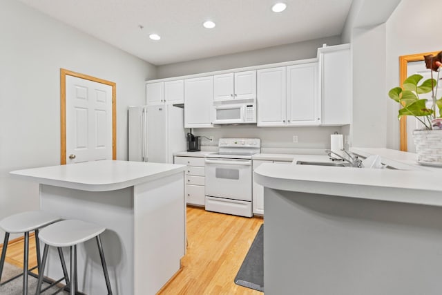 13848 52nd Ave N, Plymouth, MN 55446 - kitchen with white appliances, a breakfast bar area, white cabinetry, a sink, and light wood-type flooring