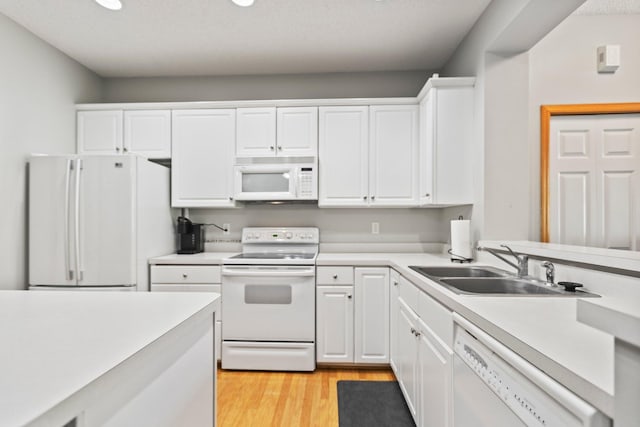 13848 52nd Ave N, Plymouth, MN 55446 - kitchen featuring white appliances, white cabinets, light countertops, a sink, and light wood-style flooring