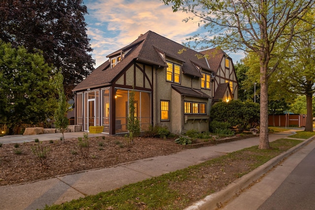 2901 Vincent Ave N, Minneapolis, MN 55411 - english style home with a sunroom, a shingled roof, stucco siding, and concrete driveway