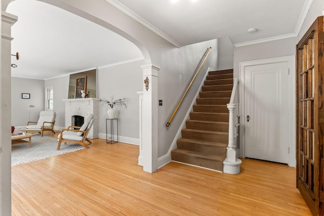 2901 Vincent Ave N, Minneapolis, MN 55411 - stairway featuring arched walkways, wood finished floors, crown molding, a brick fireplace, and baseboards