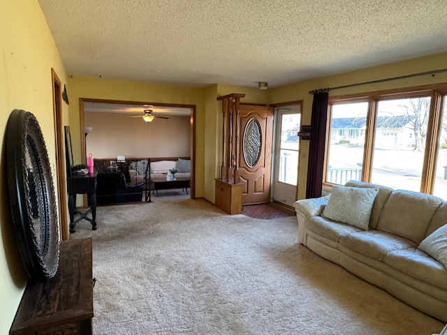 living room featuring a textured ceiling, carpet floors, and ceiling fan