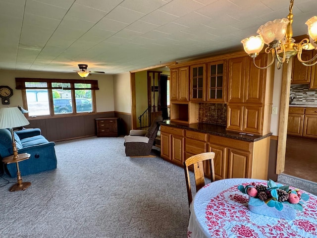 1001 Birch Ave, Olivia, MN 56277 - dining room with carpet flooring, a chandelier, wainscoting, wooden walls, and stairs