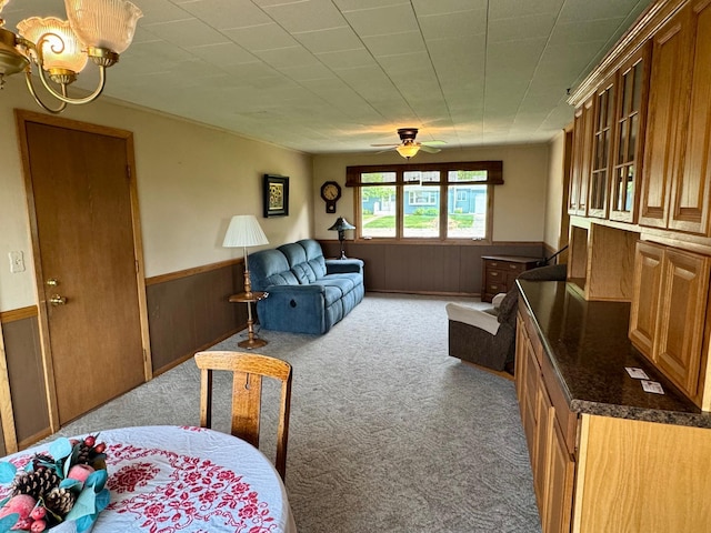 1001 Birch Ave, Olivia, MN 56277 - carpeted living area featuring a wainscoted wall, wooden walls, ceiling fan, and a chandelier