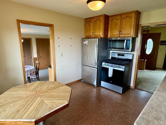 1001 Birch Ave, Olivia, MN 56277 - kitchen featuring appliances with stainless steel finishes, brown cabinets, light countertops, and a textured ceiling