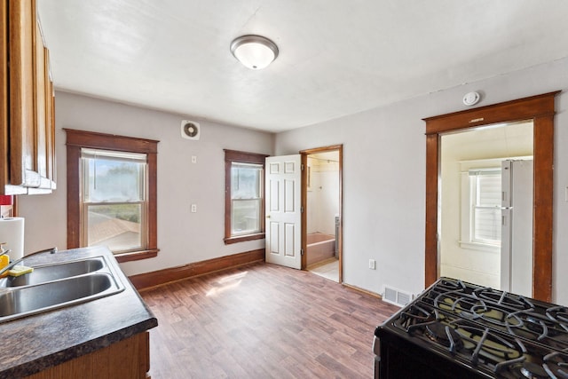 906 5th St E, Saint Paul, MN 55106 - kitchen with black gas stove, freestanding refrigerator, a sink, and wood finished floors