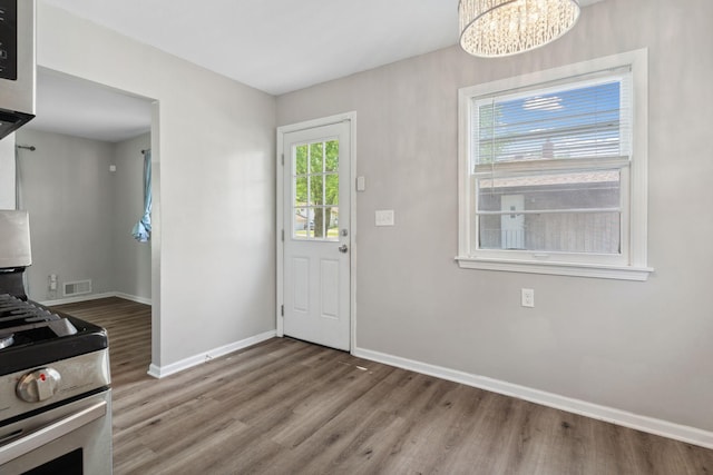 2237 Holloway Ave E, North Saint Paul, MN 55109 - kitchen featuring wood finished floors, stainless steel range with gas stovetop, a chandelier, and baseboards